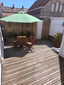 a patio with a table and an umbrella at La maison du 116 in Gravelines
