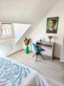 a bedroom with a bed and a desk and a chair at La maison du 116 in Gravelines