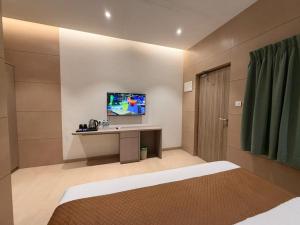 a bedroom with a desk and a tv on a wall at Shelter Suites - Formerly known as Fisco The Hub Link in Mumbai