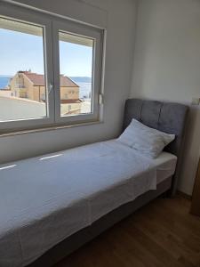 a bed in a room with a large window at Apartments Malou in Baška Voda