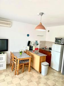 a kitchen with a table and a refrigerator at résidence Fogata in LʼÎle-Rousse