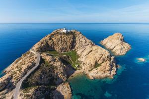 an island in the ocean with a lighthouse on it at résidence Fogata in LʼÎle-Rousse
