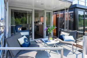 a screened in porch with chairs and a table at Tiny Olav houseboat close to the beach and restaurants by Weltevreden Experience in Zeewolde