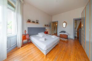 a bedroom with a white bed and a wooden floor at Le Grand Rivage in Verdun-sur-Meuse