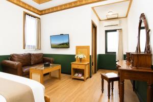 a room with a bed and a couch and a table at Kangen Boutique Hotel in Yogyakarta