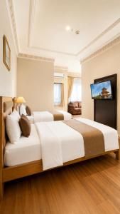 a bedroom with two beds and a flat screen tv at Kangen Boutique Hotel in Yogyakarta