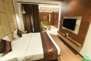 a hotel room with a bed and a flat screen tv at Maple Grand in Agra