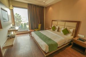 a hotel room with a bed and a large window at Maple Grand in Agra +85 photos