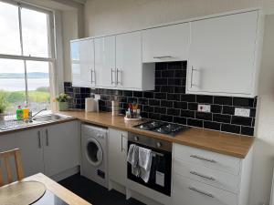 a kitchen with white cabinets and a washer and dryer at Prime Dundee West End 3BR Apartment, Stunning River Views, Sleeps 6 in Dundee +17 photos