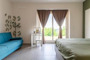 a bedroom with a blue couch and a large window at Lanizoladelroero in Sommariva Perno