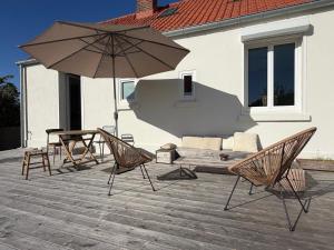 a patio with a couch and an umbrella and chairs at Maison semi individuelle avec jardin in Ambleteuse
