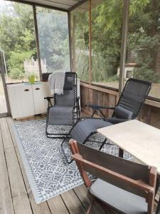 a screened in porch with chairs and a table at Ancienne Gare Camargue in Arles