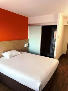 a bedroom with a white bed and a red wall at HubOne3 Istres in Istres