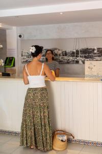 a woman is standing at a counter in a restaurant at Hostal Cala Ratjada in Cala Ratjada