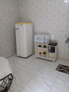 a white refrigerator in a room with a microwave at Kit net familiar in Vitória