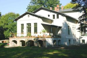 a large white house with a porch on a lawn at Gutshaus Bartelshagen in Bartelshagen