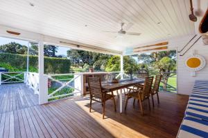 a dining room with a table and chairs on a deck at Parkview Cottage Portsea in Portsea