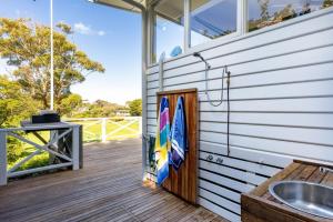 a porch with a surfboard on the side of a house at Parkview Cottage Portsea in Portsea +13 photos