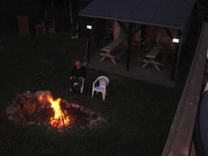 a man sitting in a chair next to a fire at Ferienwohnung am Kreßinsee in Strietfeld