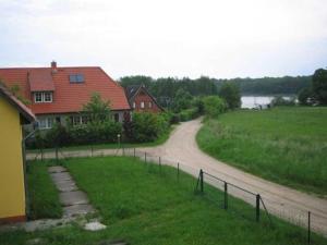 a house with a dirt road next to a field at Ferienwohnung am Kreßinsee in Strietfeld