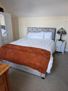 a bedroom with a large bed with an orange blanket at Townhouse Sleeps 8 - Garden Wifi Free Parking in Belmullet