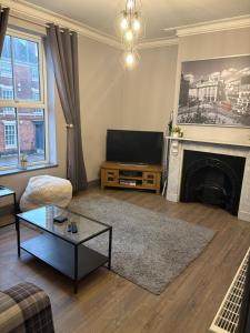 a living room with a television and a fireplace at Impressive City Centre Apartment in Derby