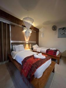 a bedroom with two beds and a chandelier at Toba Village Inn in Tuktuk Siadong