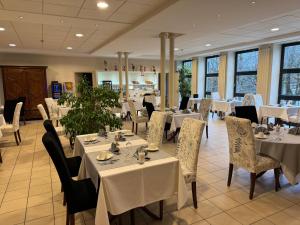 a dining room with white tables and chairs and windows at HOTEL CERISE - LES SOURCES Luxeuil-les-Bains in Luxeuil-les-Bains