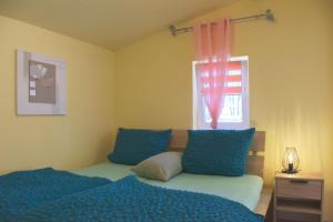 a bedroom with a bed with blue pillows and a window at Ferienhaus An der Riede in Bedekaspel +21 photos