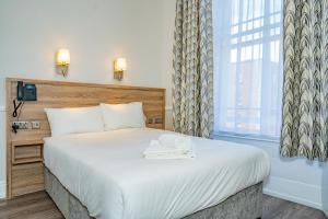 a bedroom with a large white bed with a window at Iveagh Lodge in Dublin