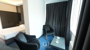 a hotel room with a bed and two chairs and a table at Grand Urfa Hotel in Urfa
