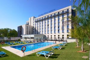 a hotel with a swimming pool in front of a building at M.A. Hotel Sevilla Congresos in Seville