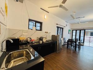 a kitchen with a sink and a living room at Fort Grande INN in Fort Kochi