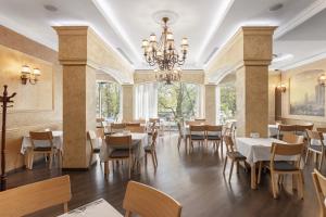 a restaurant with tables and chairs and a chandelier at Alexandrovskiy Hotel in Odesa