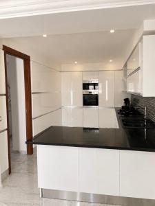 a kitchen with white cabinets and a black counter top at Villa Élégance in Tunis