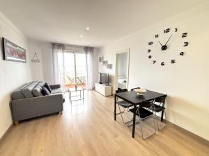 a living room with a table and a clock on the wall at Rhode 2a in Roses