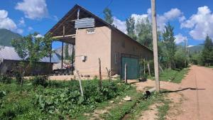 a building with a green door next to a dirt road at Belek Gust house in Toktogul