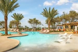 a pool at a resort with chairs and palm trees at Hotel Solea, Autograph Collection in Carlsbad