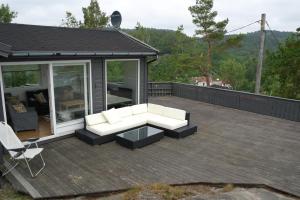 a patio with a couch and a table on a deck at Havblikk, cozy cabin by the sea with beautiful views in Mandal