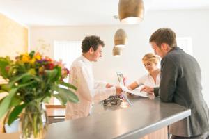 een groep van drie mensen die rond een keukenaanrecht staan bij Hotel Restaurant Bären in Isny im Allgäu