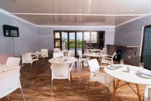 a dining room with white tables and white chairs at 606 Guesthouse in Bushbuckridge