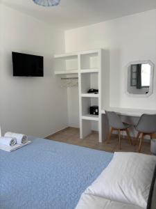 a bedroom with a bed and a desk and a television at Tarelis Beach Apartments & Studios in Kamari