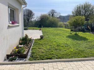 a yard with a lawn with flowers and a house at Gîte Ghislaine in Péaule +1 photo
