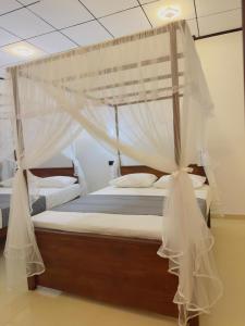 a bedroom with two beds with mosquito nets at Hotel Elysian in Udawalawe