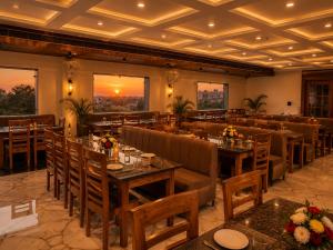 a restaurant with tables and chairs with a sunset in the background at Hotel Grand Lucent Mathura-Vrindavan in Gokul