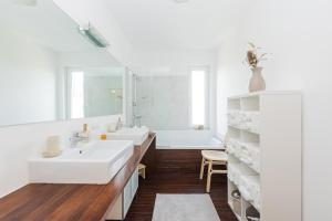 a white bathroom with two sinks and a tub at Helles Penthouse mit Dachterrasse & Bergblick in Mondsee +60 photos