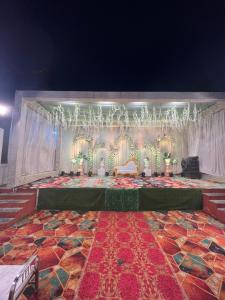 a room with a stage with chairs and a table at Hotel Grand Barrack in Khandwa