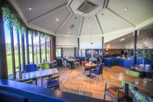 a restaurant with tables and chairs and windows at Forest Hills Hotel & Country Club in Frodsham