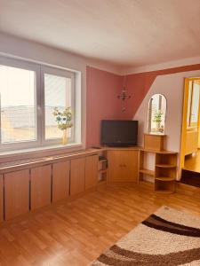 a living room with a flat screen tv and two windows at Apartmán Kristínka in Lendak