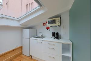 a kitchen with a sink and a refrigerator at Casa da Baixa by PURUS in Coimbra